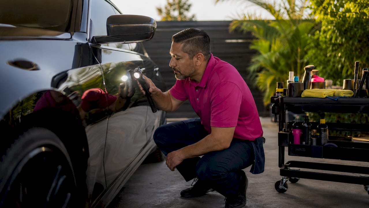 Professional inspecting luxury car paint finish