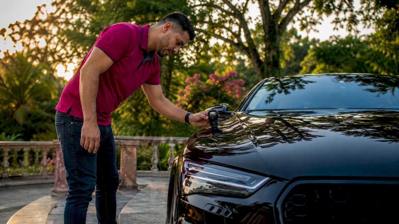 Automotive detailer measuring car gloss outdoors