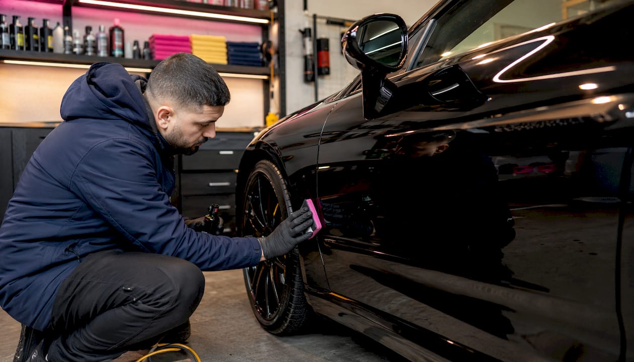 Detailer applying coating to luxury car wheels