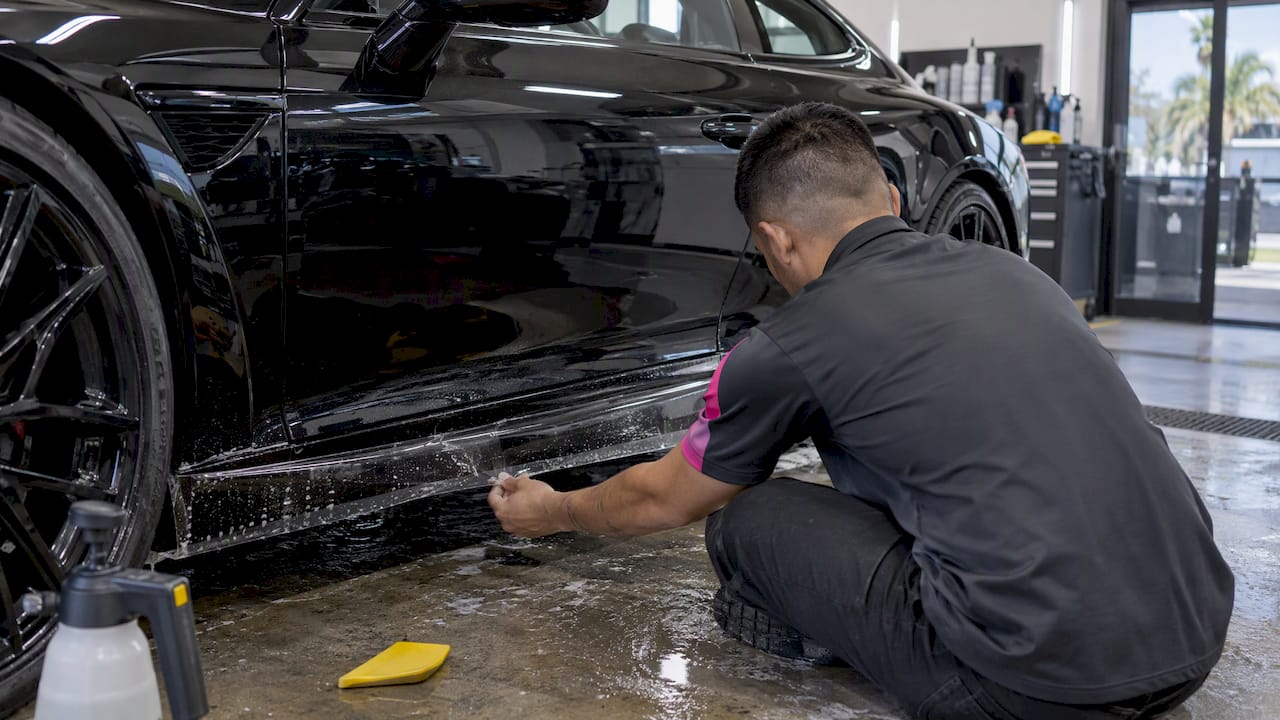 Technician applying film to luxury car rocker panel